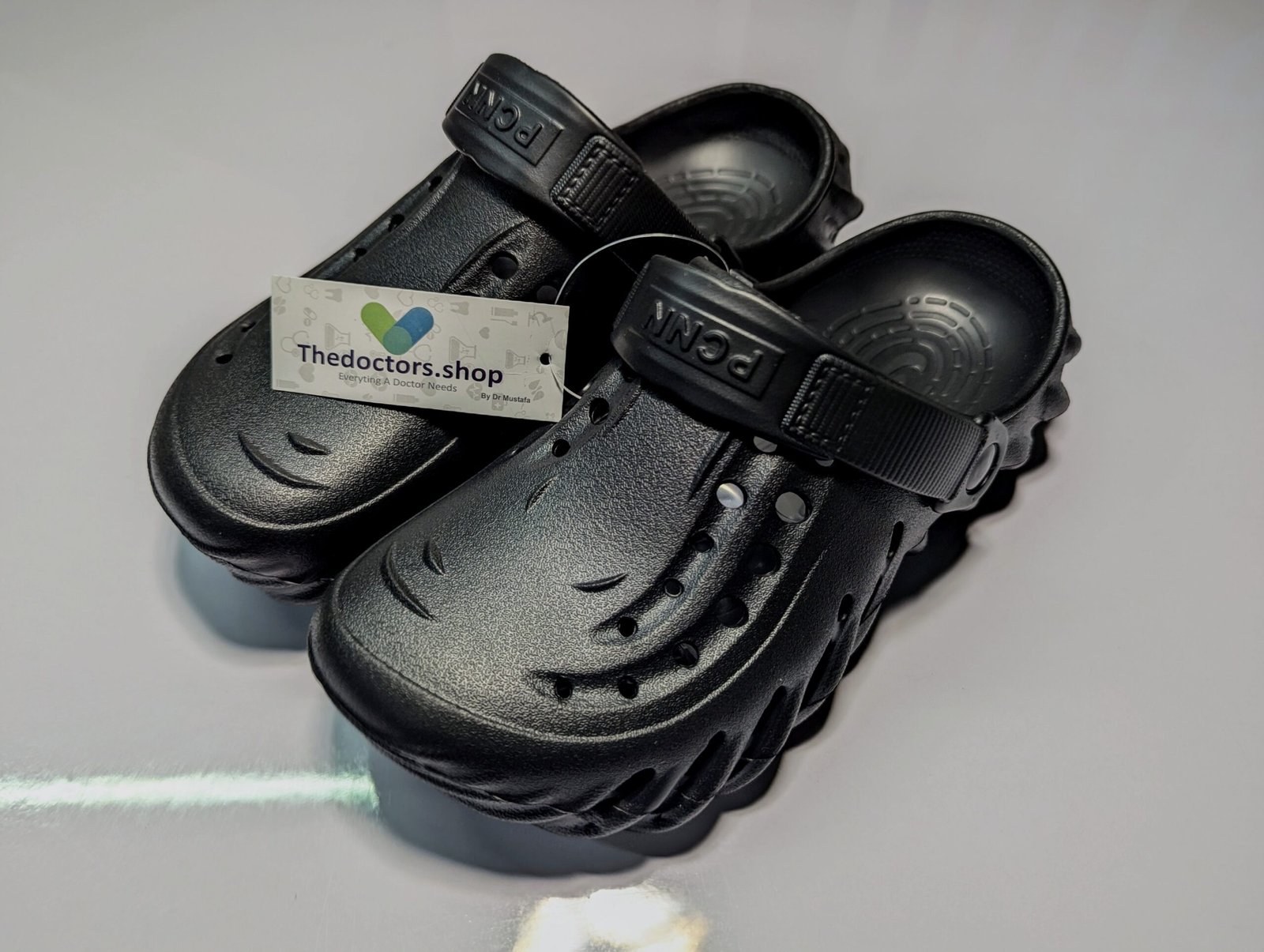 Pair of beige PGM medical clogs with ventilation holes and adjustable heel strap, displayed with TheDoctors.shop tag